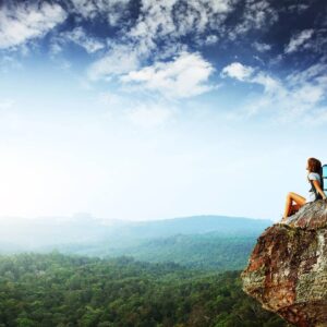 A person sitting on top of a rock.