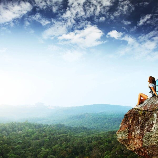 A person sitting on top of a rock.