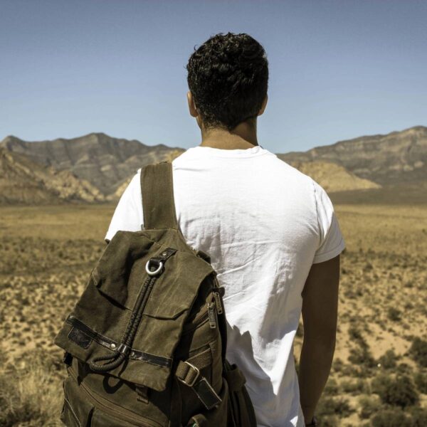 A man with a backpack standing in the desert.