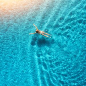 A person swimming in the ocean with their arms out.