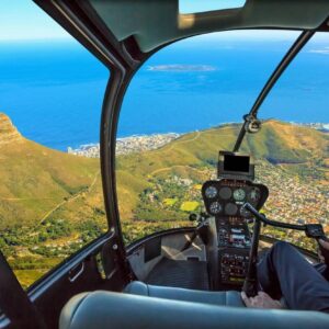 A helicopter flying over the ocean with a view of land.