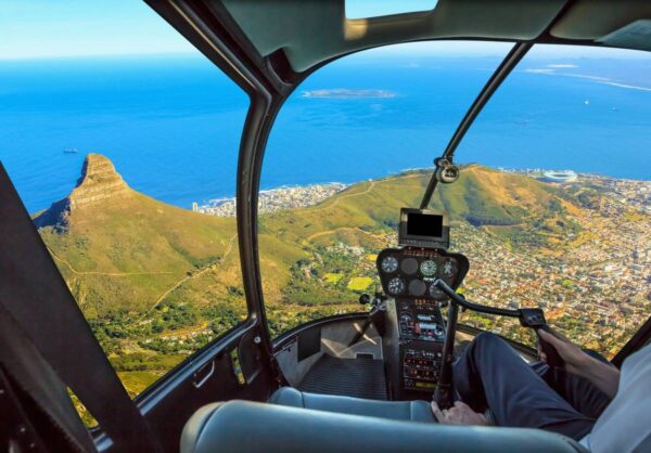 A helicopter flying over the ocean with a view of land.