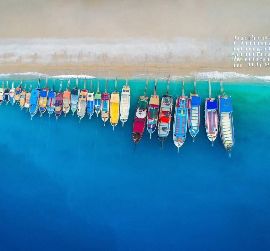 A group of boats are lined up on the water.